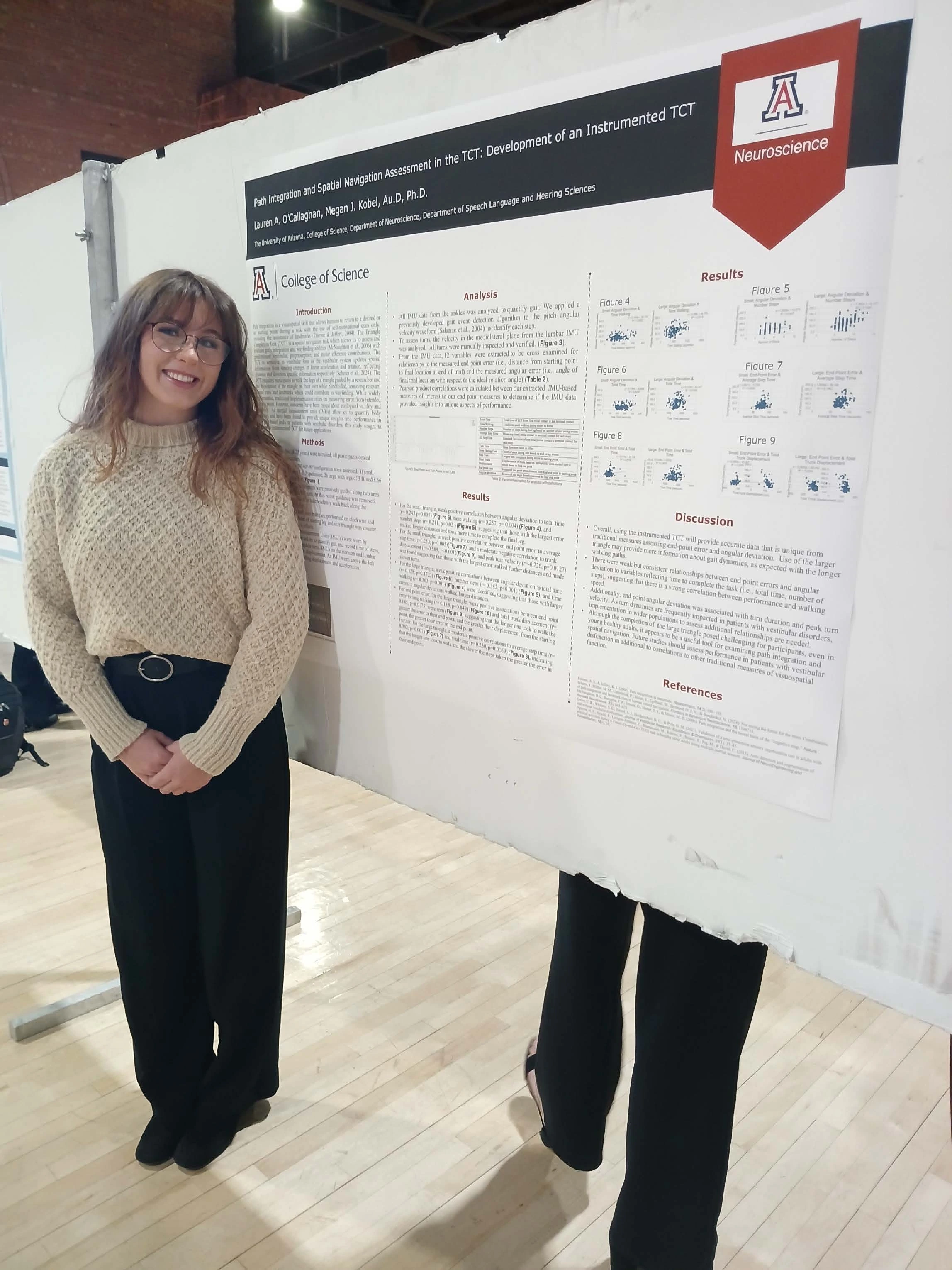 Undergraduate student standing next to their Capstone Project