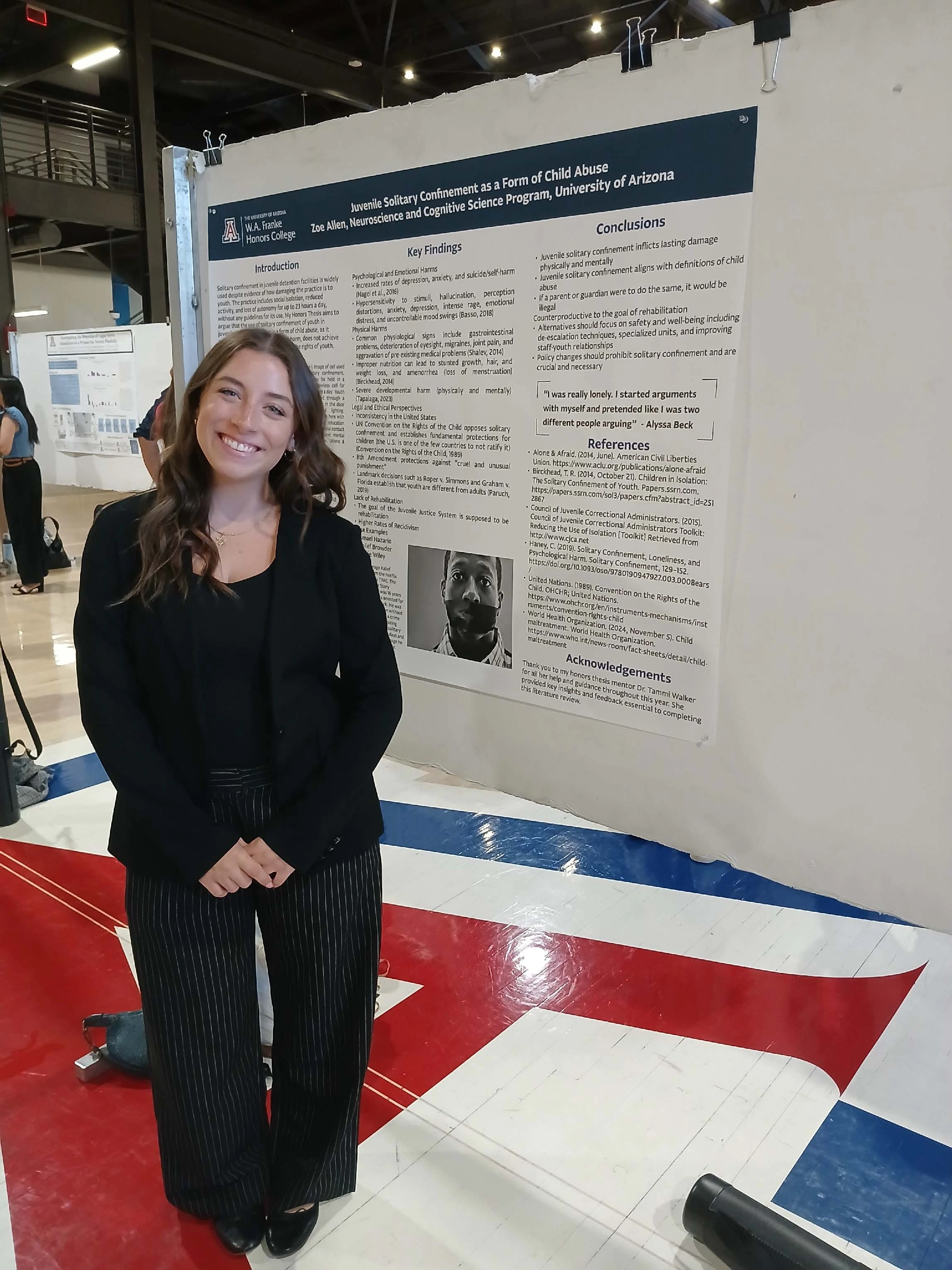 Undergraduate student standing next to their Capstone Project